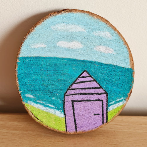 beach hut and sea painting on a wood slice