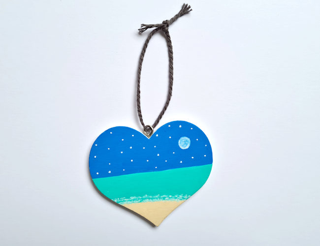 Hanging wooden heart with a beach, sky full of stars and Moon created with acrylic marker pens